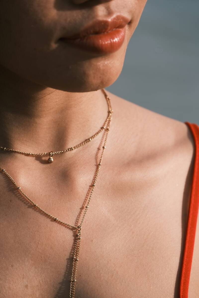 A woman wearing a gold necklace faces the sunset at a beach on Phuket, Thailand