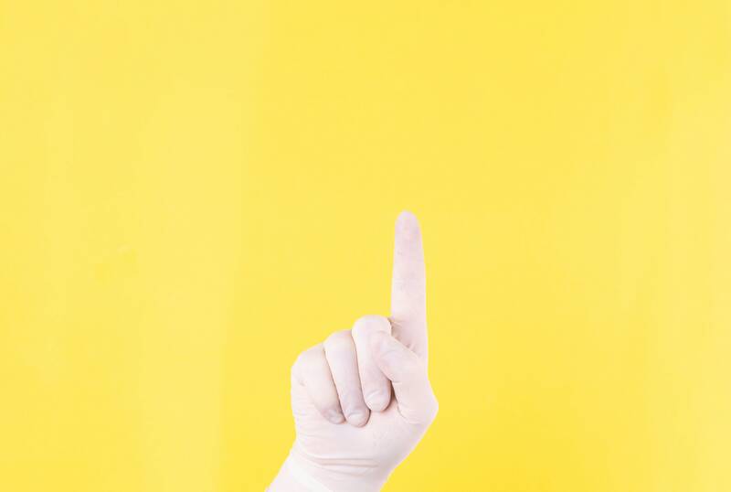 The close plan. Doctor's hand in a white medical glove on a yellow background shows up. The medicine. Place for an inscription. Advertising. Like. Medical gloves.