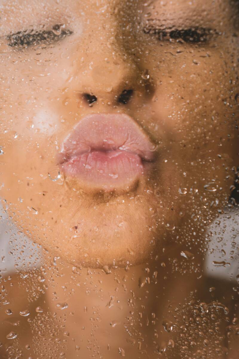 Girl kissing through rainy glass