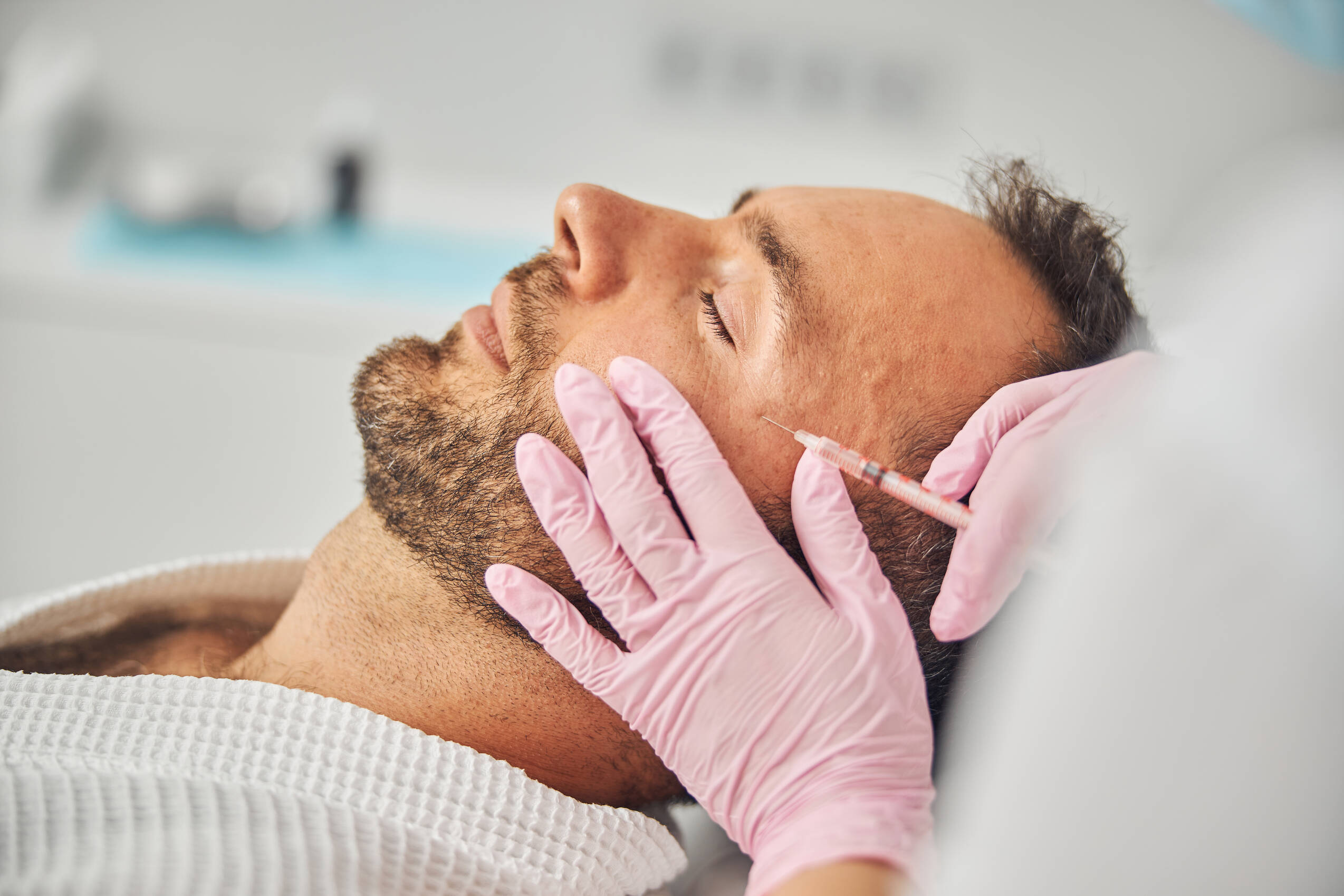 Close up female cosmetologist hands sterile gloves making injection into man face
